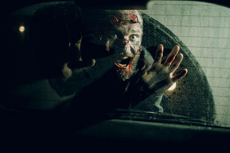 Zombie male attack car driver through vehicle window glass halloween concept.の写真素材