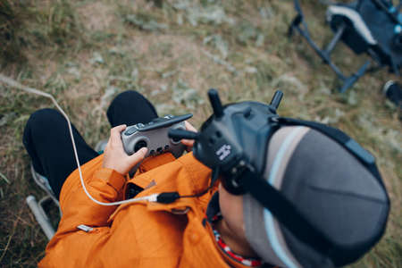 Boy controlling fpv quadcopter drone for aerial photography and videography with goggles antenna remote controller.の写真素材