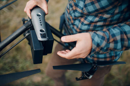 Man pilot checking quadcopter drone battery replacement and charging before aerial flight and filmingの写真素材