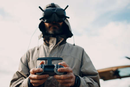 Man controlling fpv quadcopter drone for aerial photography and videography with goggles antenna remote controller.の写真素材
