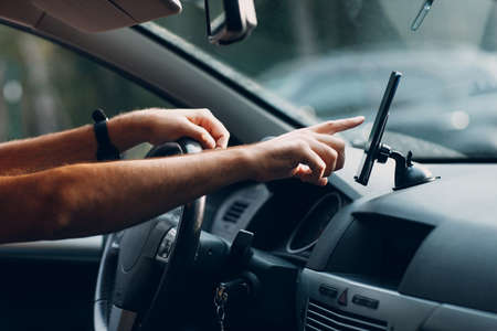 Navigator in car vehicle transportation commuter. Driver man using mobile phone navigator app driving car.の写真素材