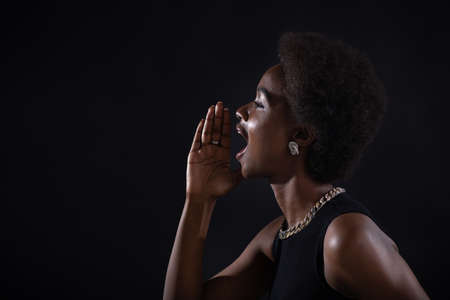 Portrait profile of black african american woman holding palm hand near wide open mouth yelling screaming calling shout black friday conceptの写真素材