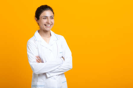 Portrait of indian doctor woman in white medical gown isolated on yellow background.