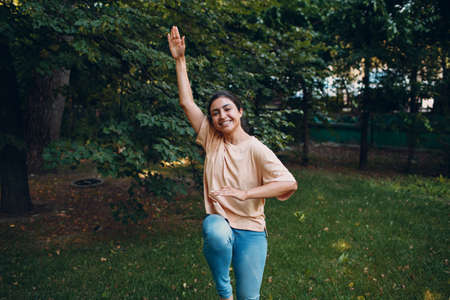 Sporty Millennial Indian Girl in Casual Clothing Stretching Before Training In Park, Doing Warming Up Exercises.の写真素材