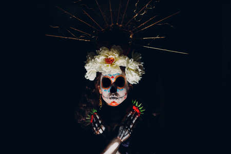 Woman with mexican skull Calavera halloween makeup on dark background. Day of the dead aka Dia de los Muertos and halloween celebrationの写真素材