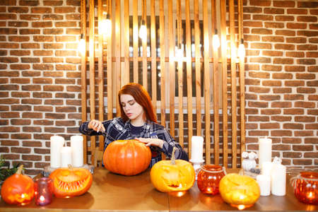 Young woman making Halloween pumpkin Jack-o-lantern. Female hands cutting pumpkins with knifeの写真素材