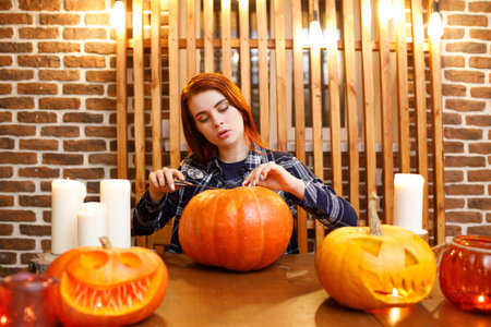 Young woman making Halloween pumpkin Jack-o-lantern. Female hands cutting pumpkins with knifeの写真素材