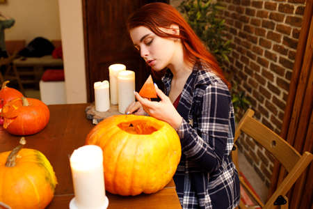 Young woman making Halloween pumpkin Jack-o-lantern. Female hands cutting pumpkins with knifeの写真素材