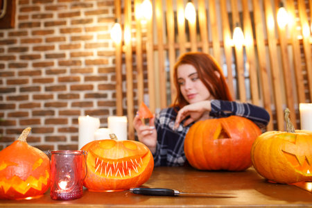 Young woman making Halloween pumpkin Jack-o-lantern. Female hands cutting pumpkins with knifeの写真素材