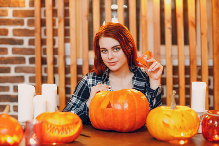 Young woman making Halloween pumpkin Jack-o-lantern. Female hands cutting pumpkins with knifeの写真素材