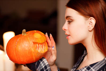 Young woman making Halloween pumpkin Jack-o-lantern with candles. Female hands cutting pumpkins with knifeの写真素材