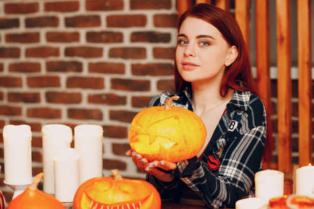 Young woman making Halloween pumpkin Jack-o-lantern with candles. Female hands cutting pumpkins with knifeの写真素材