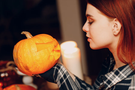Young woman making Halloween pumpkin Jack-o-lantern with candles. Female hands cutting pumpkins with knifeの写真素材