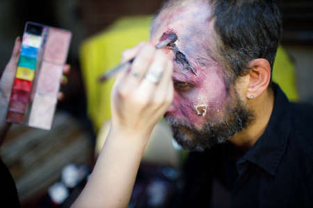 Zombie male makeup applying for halloween concept. Make up with brush and paint skin and blood faceの写真素材