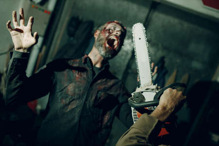 Zombie and chainsaw defence halloween concept. Make up skin and blood faceの写真素材