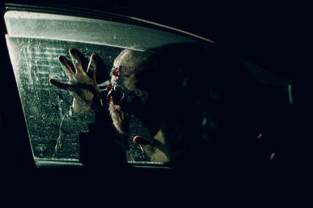 Zombie male attack car driver through vehicle window glass halloween concept.の写真素材