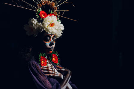 Woman with mexican skull halloween makeup on dark background. Day of the dead aka Dia de los Muertos and halloween concept.の写真素材