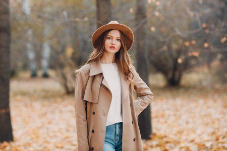 Young woman model in autumn park with yellow foliage maple leaves. Fall season fashionの写真素材