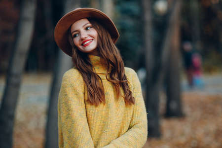 Young woman model in autumn park with yellow foliage maple leaves. Fall season fashionの写真素材