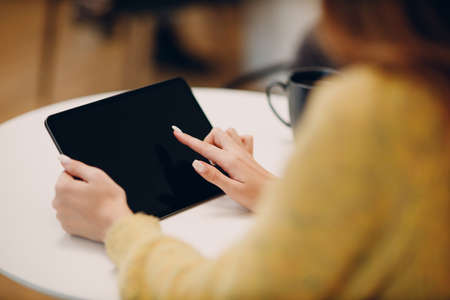 Beautiful young woman using digital tablet at cafe table with cup of coffee.の写真素材