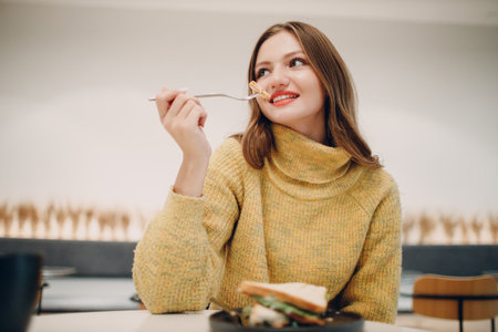 Young european woman eating sandwich at indoor cafe. Health and diet.の写真素材