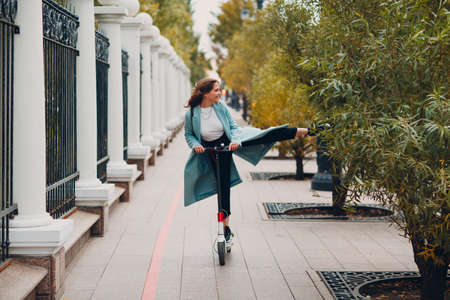 Young woman riding electric scooter in autumn city. Alternative commuter transportation.の写真素材