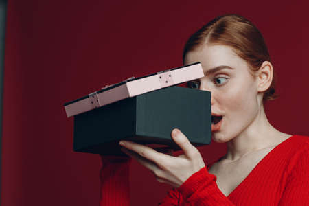 Young woman opening to christmas gift box with ribbon. Studio shot portraitの写真素材