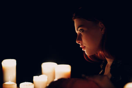 Young woman profile portrait with candles light in darkness. Edge lit faceの写真素材
