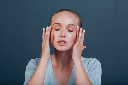 Millenial young woman blonde hair portrait doing face yoga self facebuilding massage for face skin.の写真素材