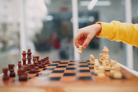 Little kids playing chess at kindergarten or elementary school. Hand holds chess figure close up.の写真素材