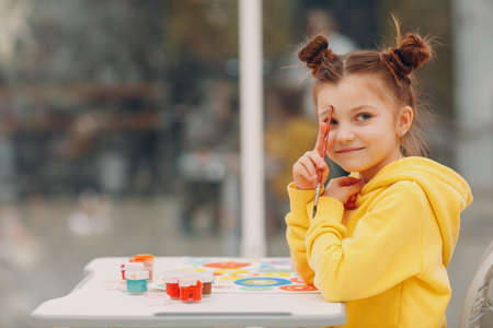 Little girl drawing art picture. Painting with brush and watercolor paintsの写真素材