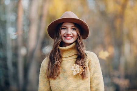 Young woman model in autumn park with yellow foliage maple leaves. Fall season fashionの写真素材