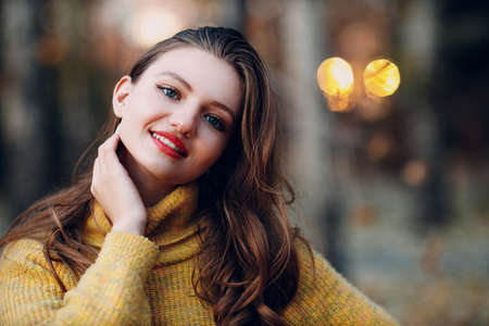Young woman 18 years old model in autumn park with yellow foliage maple leaves. Fall season fashionの写真素材