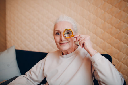 The elderly 70 years old woman with magnifier loupe in hand.の写真素材