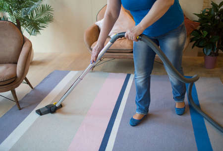 Cleaning service concept. Woman clean carpet with vacuum cleanerの写真素材
