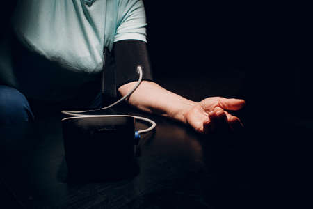 Senior woman taking measures blood pressure at night home. Self care of elderly health.