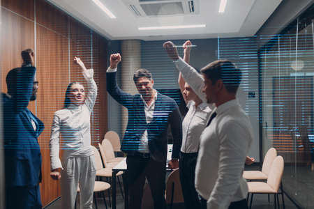 Businessman and businesswoman team doing warming up exercises before office meeting. Business healthy successful people group man and woman after conference discussion with boss.の写真素材