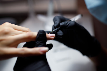 Manicure process female hands finger nails polish. Beautician in glovesの写真素材