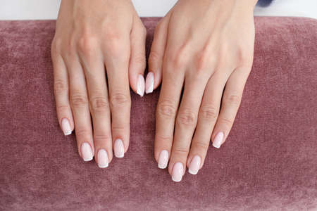 Female hand fingers nails with manicure after nail salon procedure on pink.の写真素材
