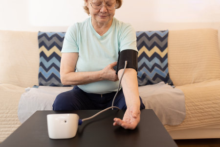 Senior woman taking measures blood pressure at home indoor. Self care of elderly health.の写真素材