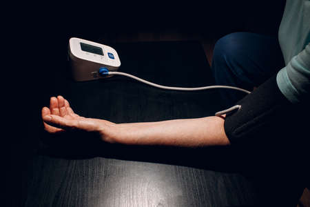 Senior woman taking measures blood pressure at home. Old hand close up. Self care of elderly health.の写真素材