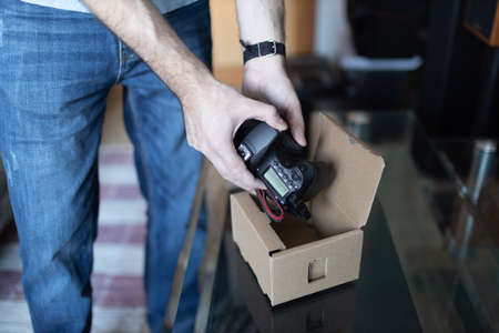 Adult man small business owner packing order box package shipping to customer. Entrepreneur packaging camera in box for delivery at home.の写真素材