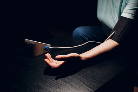 Senior woman taking measures blood pressure at home. Old hand close up. Self care of elderly health.の写真素材