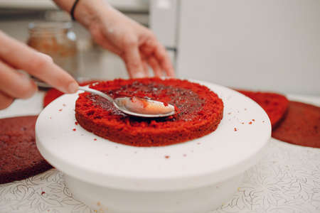 Pastry chef makes with jam delicious red velvet cake. Cooking and decorating dessert.の写真素材
