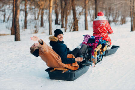 Santa claus riding snowmobile couple in love in the winter forest.の写真素材