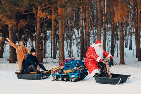 Santa claus riding snowmobile couple in love in the winter forest.の写真素材