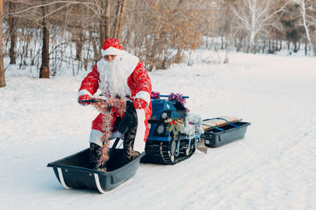 Santa claus riding snowmobile in the winter forest.の写真素材