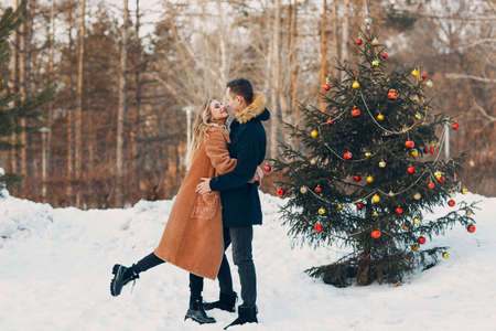 Young adult couple decorates christmas tree in winter forest. New year pine holiday party celebration conceptの写真素材