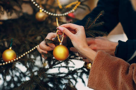 Young adult couple decorates christmas tree in winter forest. New year pine holiday party celebration conceptの写真素材