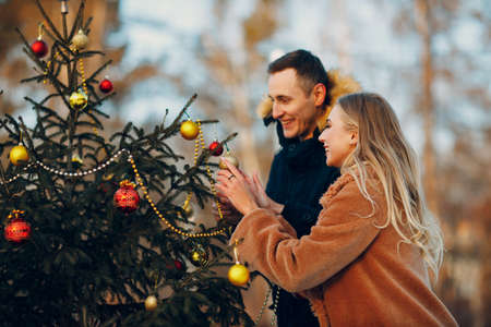 Young adult couple decorates christmas tree in winter forest. New year pine holiday party celebration conceptの写真素材
